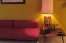 Уголок гостиной с розовым диваном и лампой.